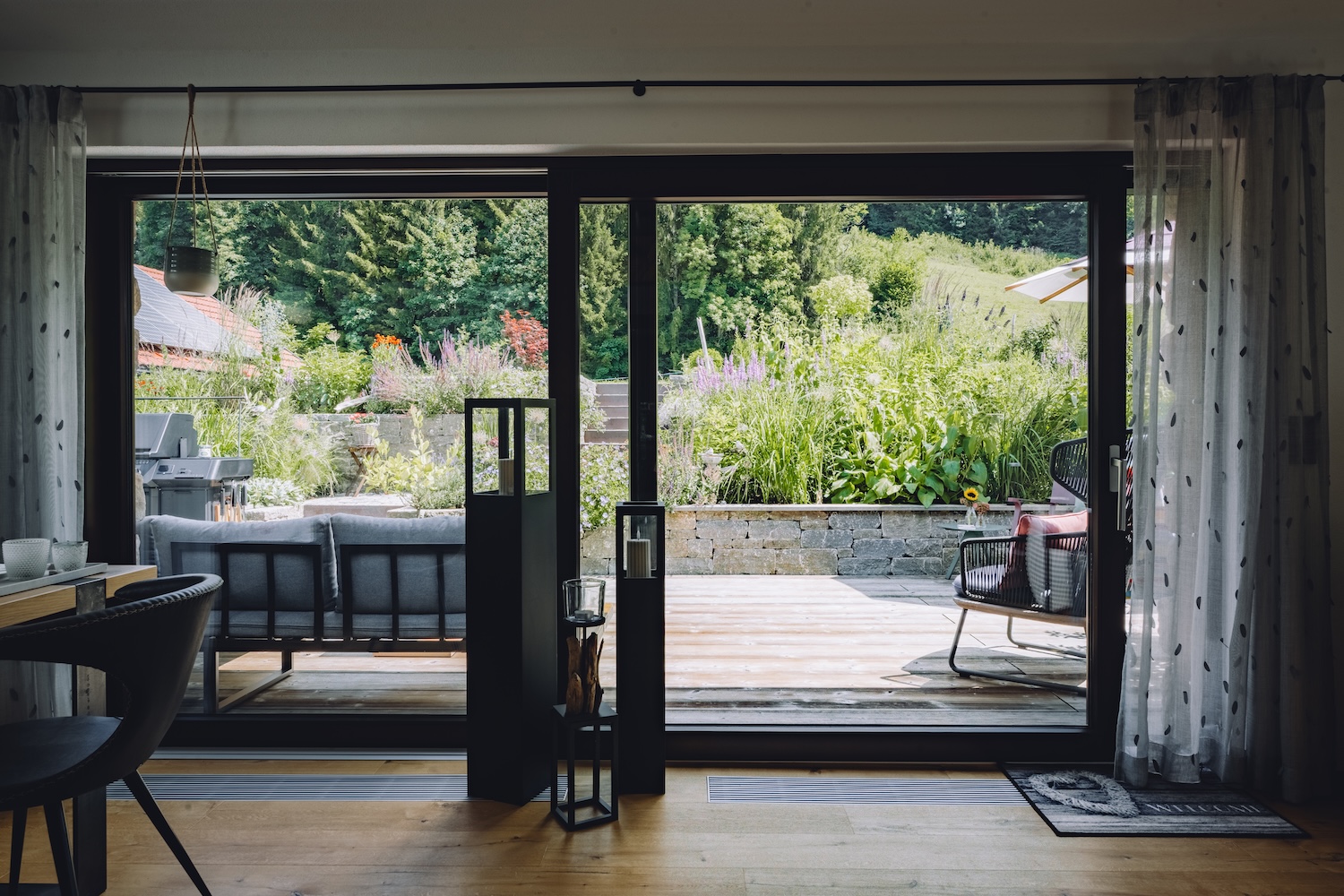 Blick aus einem Wohnzimmer durch eine große Glasfront auf die schön gestaltete Terrasse