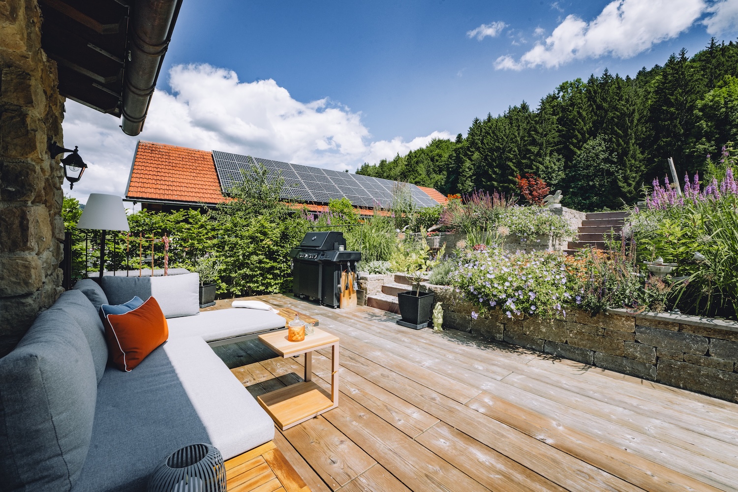 Ein Haus mit rotem Dach, Garten und Pool, umgeben von Bäumen und Hügeln.