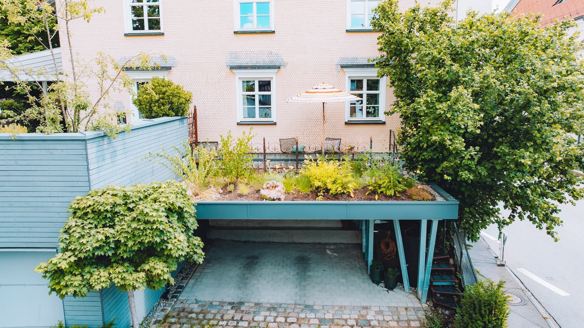 Der kleine Dachgarten in Stiefenhofen zeigt üppige Stauden, Kübelpflanzen und eine Terrasse über dem Carport.